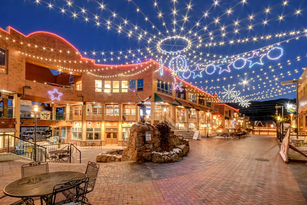 This lively scene features decorative lights, a stone fountain, outdoor seating areas, and nearby retail storefronts, capturing a festive atmosphere ideal for group outings, celebrations, or easy access to local dining and entertainment.