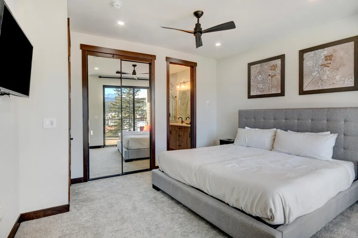 A guest bedroom with a plush bed, mirrored wardrobe, and wall art, infused with soft natural light. The room feels calm and welcoming, ideal for relaxation or a quiet night's sleep.