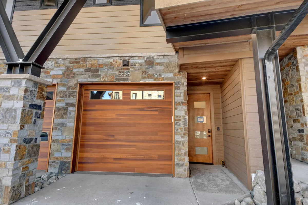 This image shows the villa’s exterior, featuring a welcoming stone facade, a wooden garage door, and the main entrance. The approach is inviting, suggesting a comfortable and spacious home well-suited to groups gathering and arriving together.